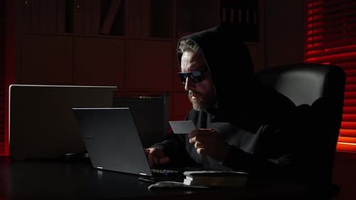 Man in Hood with Credit Card Using Laptop