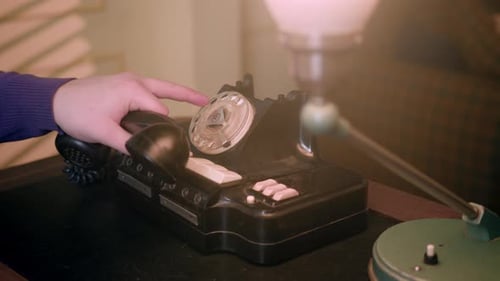 Composer un numéro sur le cadran circulaire d'un téléphone analogique noir rétro vintage dans un endroit faiblement éclairé