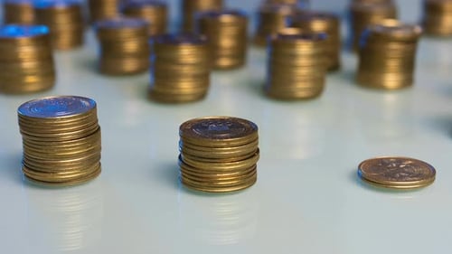A table with 3 stacks of gold coins that increase and then decrease. Money returns time lapse