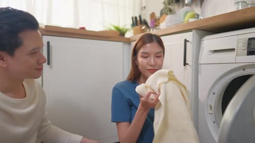 Young Couple Doing Laundry Together in Kitchen