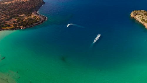 Boats glide over clear waters in a beautiful coastal bay during a sunny day in summer
