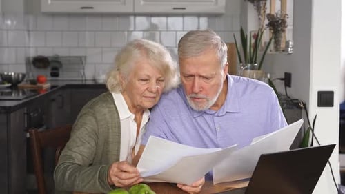Senior Couple Reviewing Documents in Kitchen