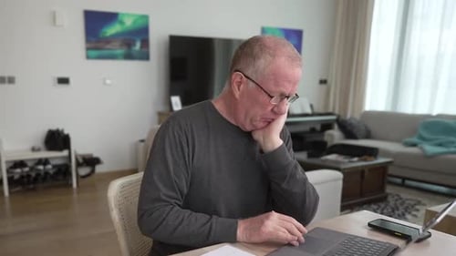 Man Working on Laptop at Home During Daytime