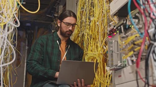 Man Works On Laptop In Server Room