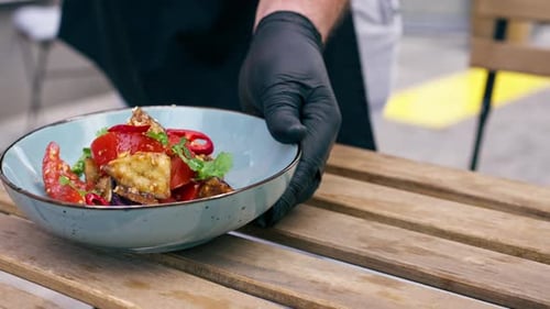in Restaurant on the Street on a Wooden Table the Chef Pours Oil Into a Warm Salad with Fried