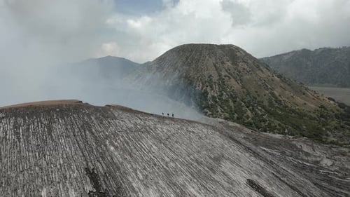 Luftaufnahme: Touristen spazieren am dampfenden Kraterrand des Mount Bromo auf Java entlang