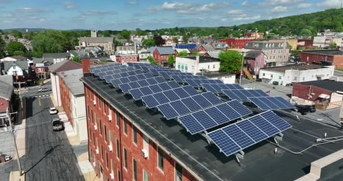 Aerial flyover of solar panels on top of roof. Small town America uses renewable energies to power g