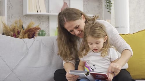 Adult and Child Reading Book on Couch