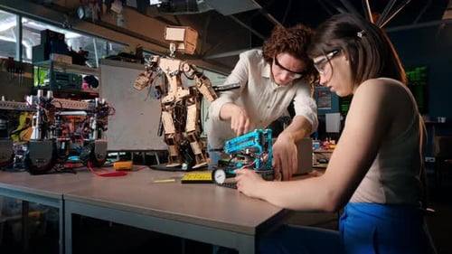 Junger Mann und Frau mit Schutzbrille bei Robotik-Experimenten in einem Labor. Robot und t