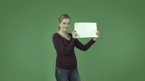 casual caucasian blond girl isolated on green smiling with blank sign