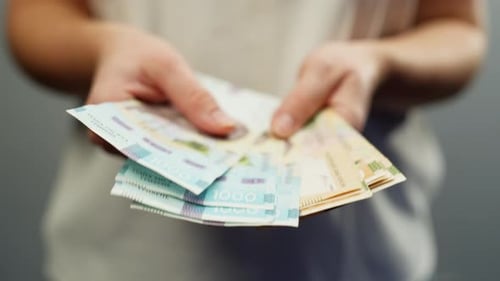 Hands Displaying and Shuffling Hryvnia Currency