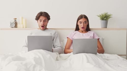 Couple Enjoying Quiet Time While Using Laptops Together in Bed