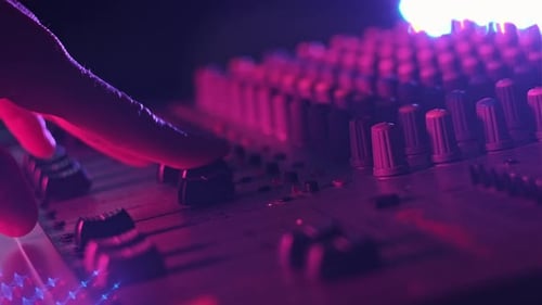 Male Hand Adjusting Faders Up And Down on Audio Mixer in Neon Light CloseUp