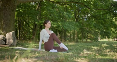 Young Beautiful Athletic Woman in Sportswear Doing Stretching and Warming Up in the Park Near a Tree