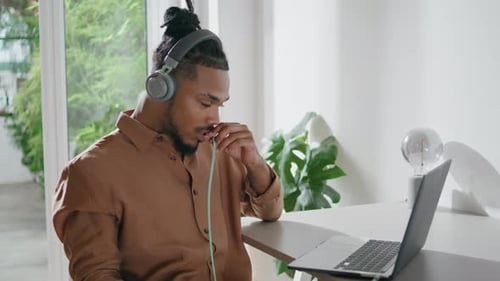Man with Headphones Video Conferencing Using Laptop