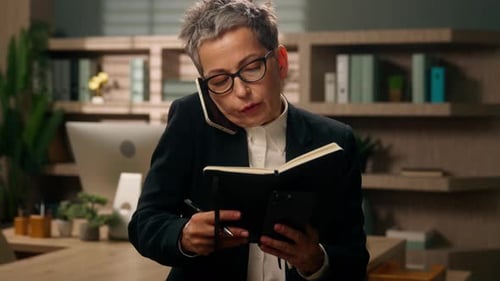 Businesswoman Taking Notes While Talking on Phone