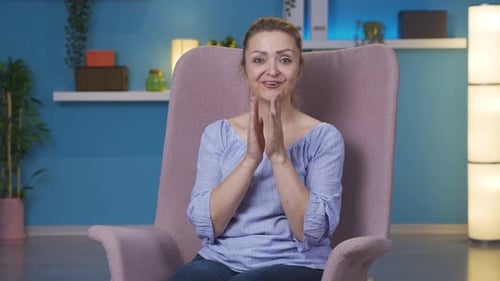 Smiling Woman Sits in Chair and Claps