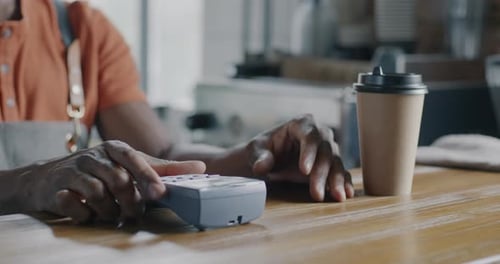 Closeup of Customer Paying for to Go Coffee with Credit Card at Counter in Modern Cafe