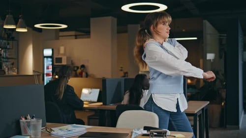 Woman Stretching at Desk in Modern Office
