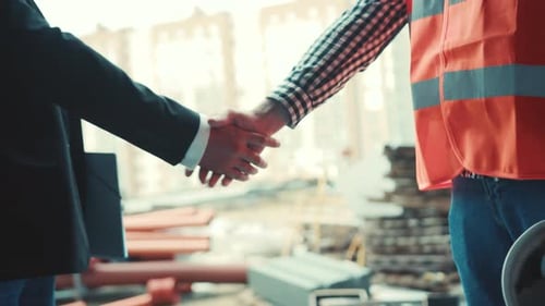 Close Up View of a Male Businessman in Suit and Male Builder Engineer in Signal Jacket Shaking Their