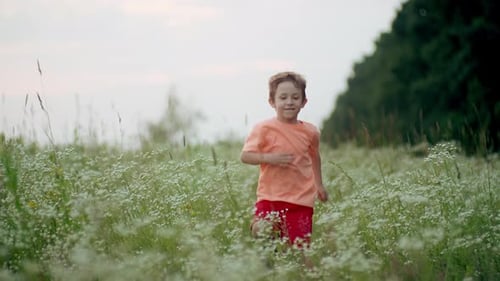 A Caucasian Boy Runs Across a Field at Sunset