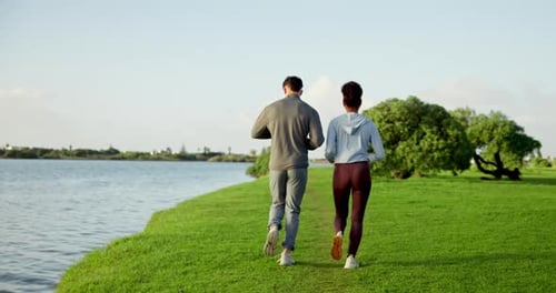 Couple Running Together by Lakeside in Sunny Park