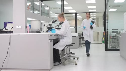 Female scientists working with microscope in modern laboratory