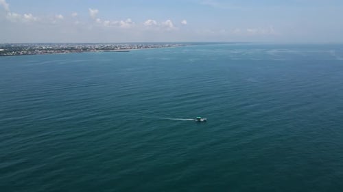 Aerial drone shot highlighting the tiny fisher boat amidst the seemingly endless ocean waves.