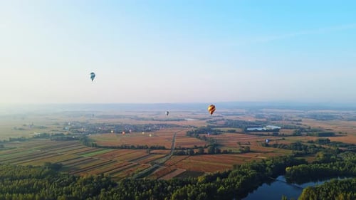 Stunning 4K aerial footage of a drone filming hot air balloons. Flying over farming fields and river