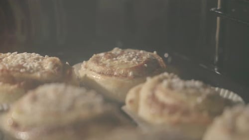 Close up of cinnamon buns getting baked in an oven with buns in the foreground
