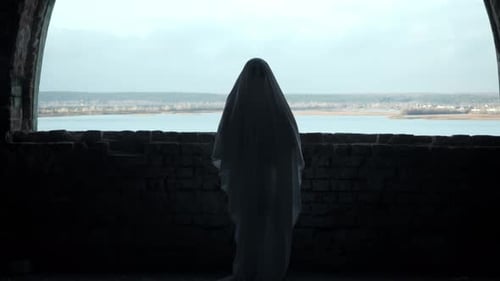 Ghost in White Sheet Stands Before Old Window Vast River and Autumn Landscape Stretching Behind