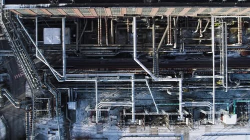 Truck driving under elevated pipe systems of a thermal power plant in winter time. Top down drone sh