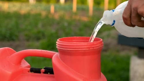 Clear Liquid Pouring into Agricultural Sprayer Outdoors