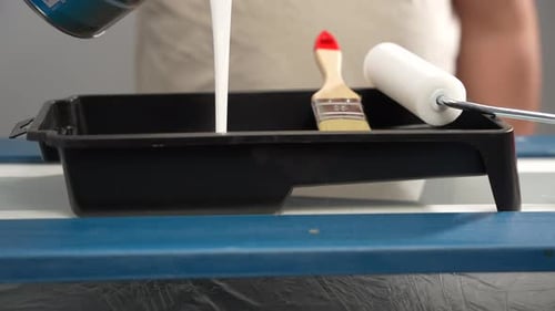 White Paint Pouring Into Black Paint Tray