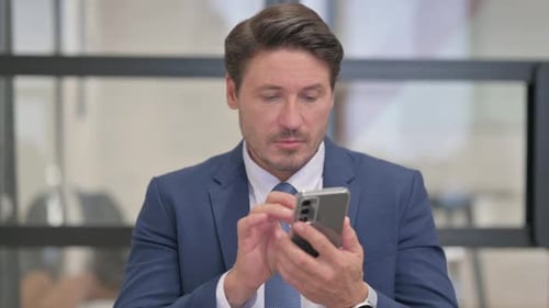 Businessman Using Smartphone in Modern Workplace Environment
