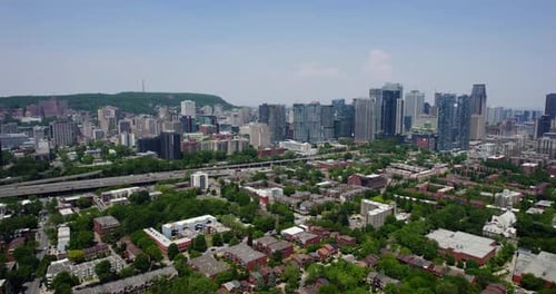 Drone shot panning over suburbs toward the downtown skyline of sunny Montreal