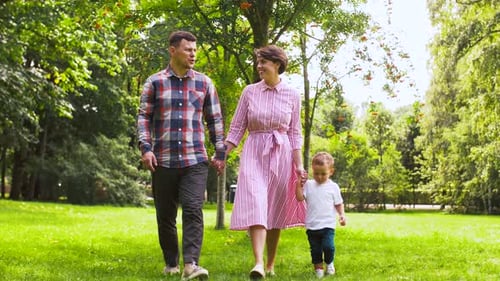 Happy young family walking together in a sunny summer park slow motion