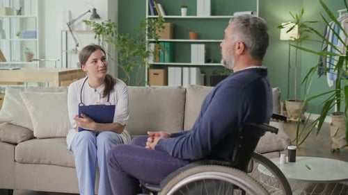 Doctor Talks With Man in Wheelchair at Home