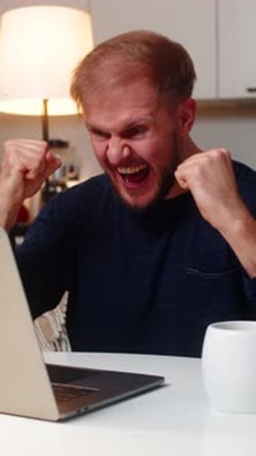 Man Reacts with Excitement to Computer Screen Indoors