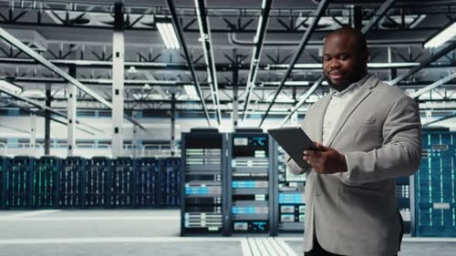 Cheerful Data Center Programmer Looking at Code Debugging Tools on Tablet