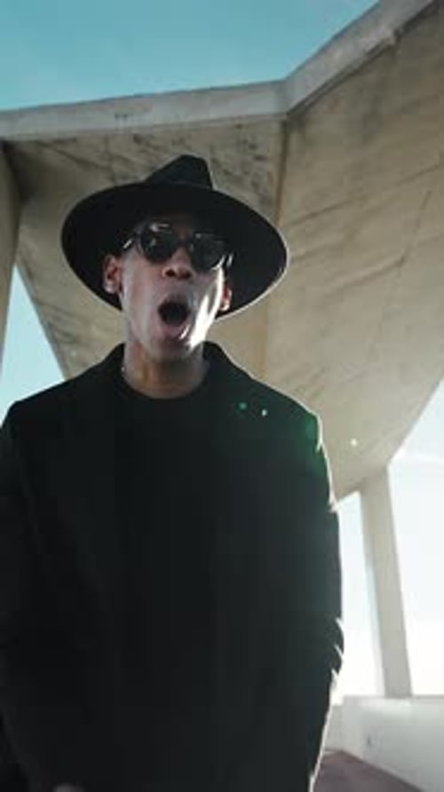 Élégant musicien hip hop afro-américain jouant et chantant sous une structure en béton