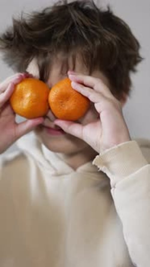 Child Puts Oranges Over Eyes Indoors
