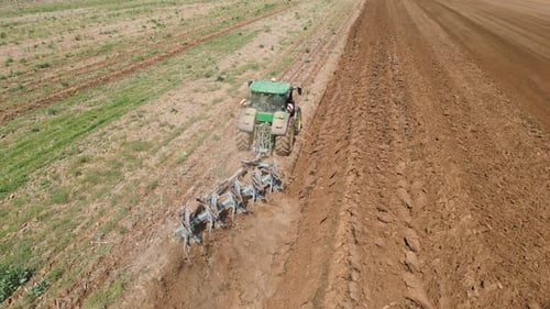 A Panoramic Drone View of a Tractor Plowing a Vast Fertile Field Illustrating How Modern Agriculture