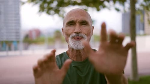 Senior Man Gesturing with Hands in Urban Park