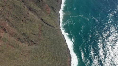 Steep sloped shoreline at Madeira with vivid blue ocean water, aerial