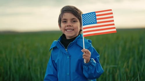 Smiling Child Waving American Flag in Field