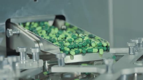 Green capsules move along the metal automatic conveyor