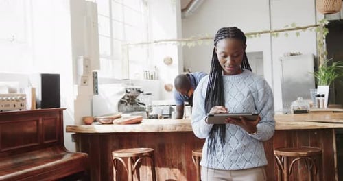 Portrait of african american woman using tablet and smiling at coffee shop, slow motion
