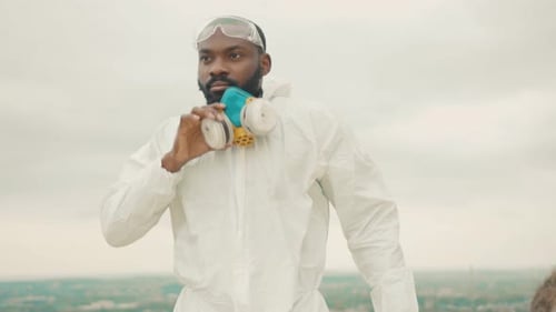 Scientist Wearing Full Chemical Protection Hazmat and Respirator Face Mask Walking Alone on Hill Top