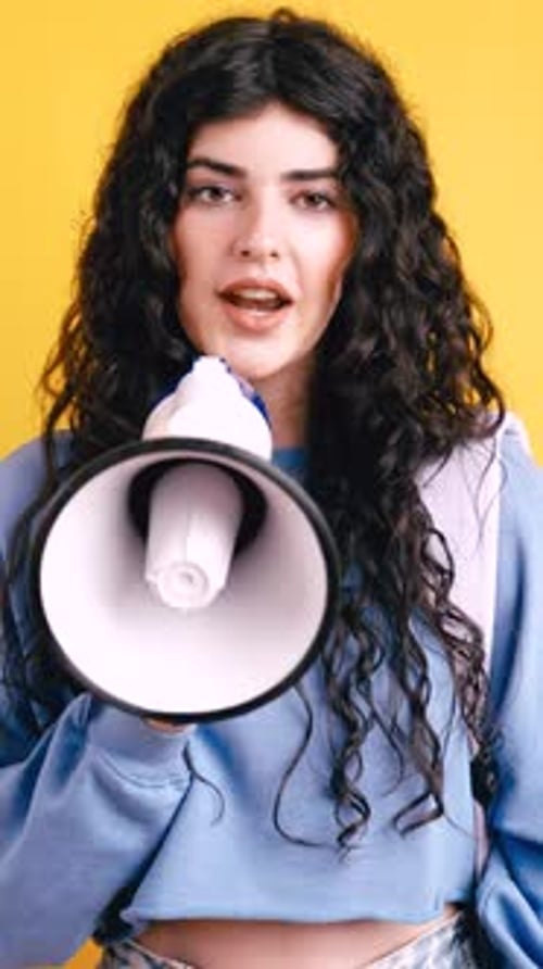 Woman Speaking into Megaphone on Yellow Background